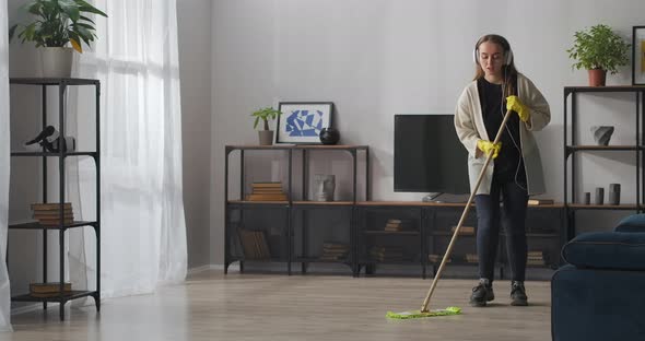 Positive Teen Girl Is Washing Floor in Apartment Listening To Music By Headphones and Player Doing alt