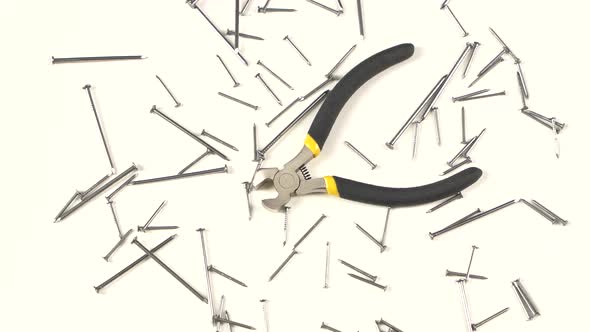 Wire Cutters with Yellow, Gray Handle on White Among Nails, Rotation, From Above alt