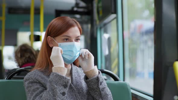 Woman Follows Modern Precautions and Wears a Medical Mask and Gloves While Traveling on Public Bus alt