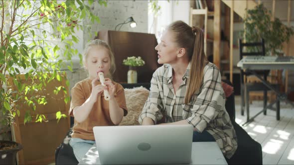 A Woman Helps Her Daughter in a Music Lesson