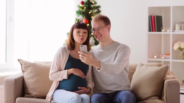 Man and Pregnant Woman Taking Selfie on Christmas alt