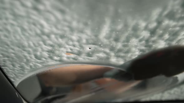 Closeup Windshield with White Foam and Female Hand Rubbing Glass Cleaning Vehicle alt