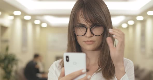 Close-up of Beautiful Brunette Businesswoman with Brown Eyes Reading on Smartphone. Portrait of alt