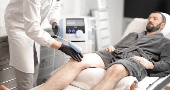 Doctor Doing Magnetic Therapy on Male Knee alt