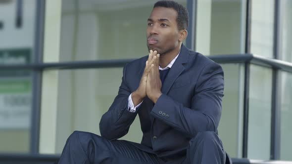 Depressed, sad young black businessman outside the office alt