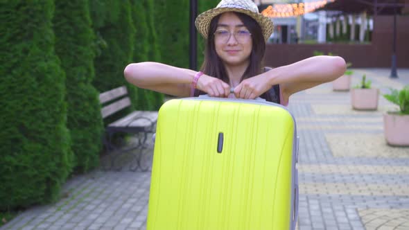 Portrait of a Smiling Asian Girl Traveler with a Suitcase in His Hand Slow Mo alt