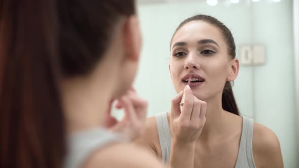 Makeup. Woman Applying Liquid Lipstick On Lips At Bathroom alt
