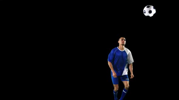 Athlete practicing soccer against black background alt