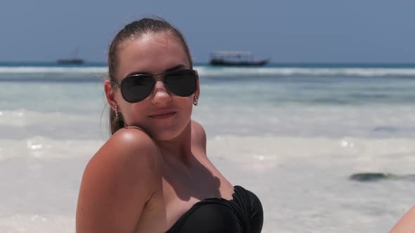 Young Woman in Black Bikini Tans on a Paradise White Sandy Beach Lies By Ocean alt