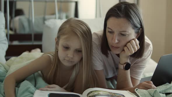 Mom and Daughter Read a Book in Bed