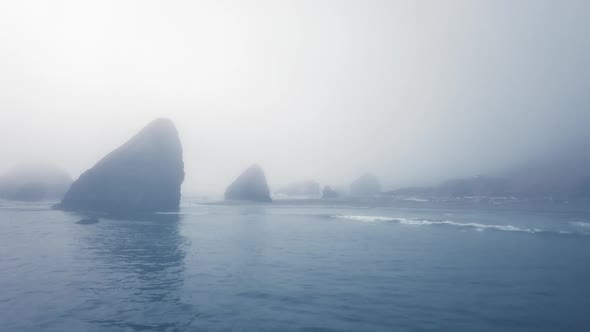 Dronе shot calm ocean near a rocky shore in heavy fog (Ariya's Beach, Oregon, USA) alt