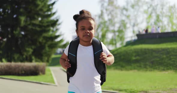 Schoolgirl with a Backpack Runs Home in the Park From Her School Dream on a Sunny Day alt