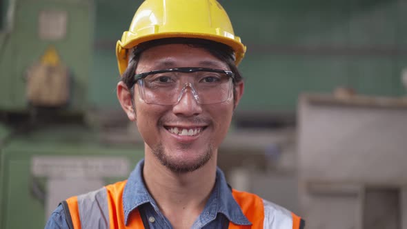 Asian male mechanic worker smiling to camera in the factory