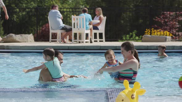 Family playing and splashing in backyard pool