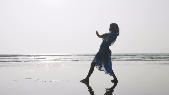 Silhouette of young woman dancing with gymnastic elements at the sandy beach
