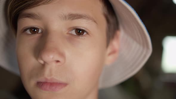 Portrait of a Serious Scared Boy in a Hat Looking at the Camera Indoors alt
