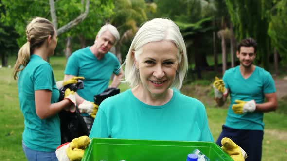 Senior woman holding a recycle bin alt