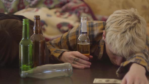 Young Bad Looking Friends Lying on the Table Near Empty Alcohol Bottles alt