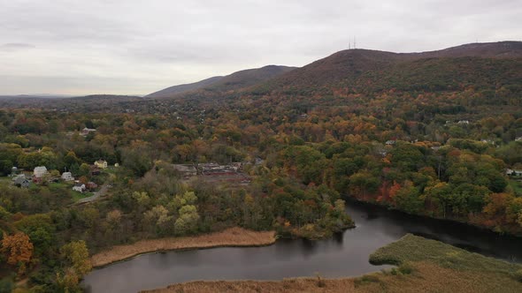 A high angle drone shot of the colorful fall foliage in upstate NY. The camera dolly in over to a st alt