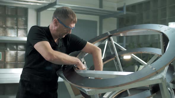 Professional worker assembles a metal structure in a private factory