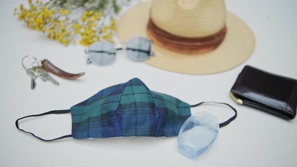 A slow pan of personal items including a face mask, hand sanitizer, keys, hat and wallet alt