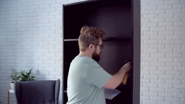 Bearded Man Assembling New Furniture at Home alt