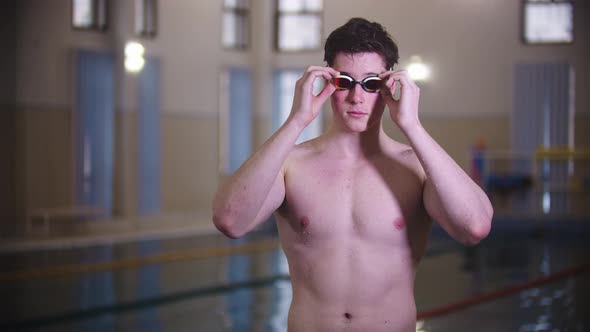 A Man Swimmer Puts on His Goggles By the Pool alt