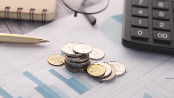 Stack of Coins Financial Graph Calculator and Notepad on Table alt