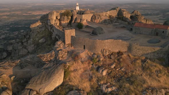 Monsanto castle and surrounding landscape at sunrise, Portugal. Aerial backward ascendent alt