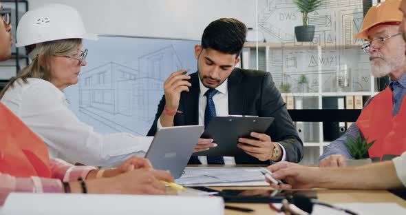 Main Engineer Signing Construction Report from Female Architect During Joint Meeting alt