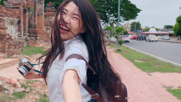 Asian backpacker blogger woman hold camera hold boyfriend hand with happy smile excited travel. alt