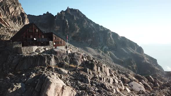 Orny cabine in the swiss alps with rocky mountains during a sunset. Aerial drone view alt
