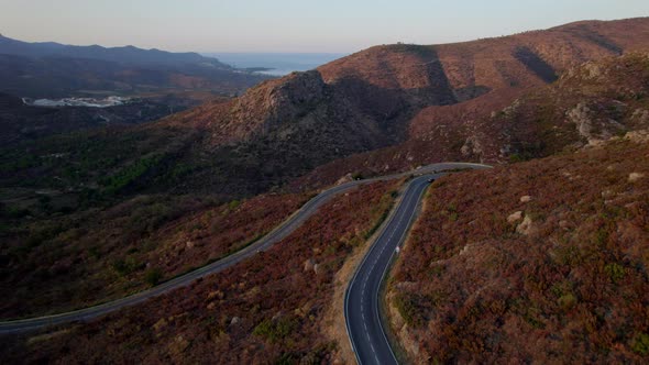 Drone Of Single Car Driving Along Empty Winding Road alt