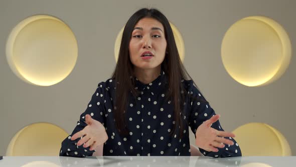 Smiling Asian Worker Sitting at a Desk in the Office and Looking at the Camera alt
