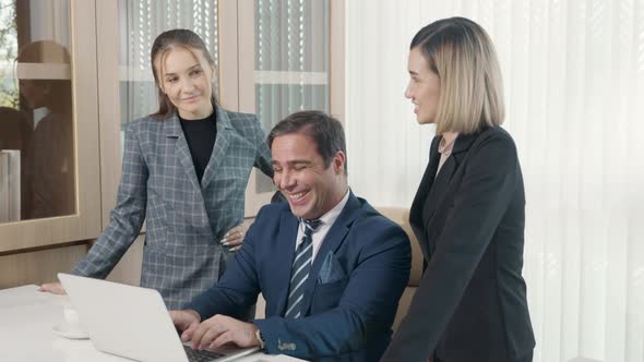 Group of young business people working on desk together with one laptop in office alt