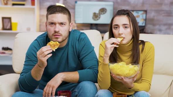 Scared Couple While Watching Tv and Eating Junk Food alt