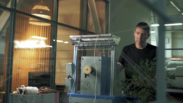 Professional worker of a private clothing production works at a loom