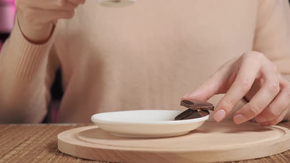 A Woman Drinks Coffee in a Cafe and Drinks Coffee with Dark Chocolate