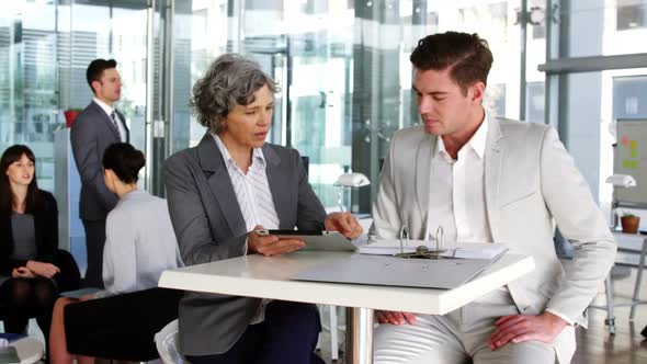Businesswoman discussing over digital tablet with colleague alt