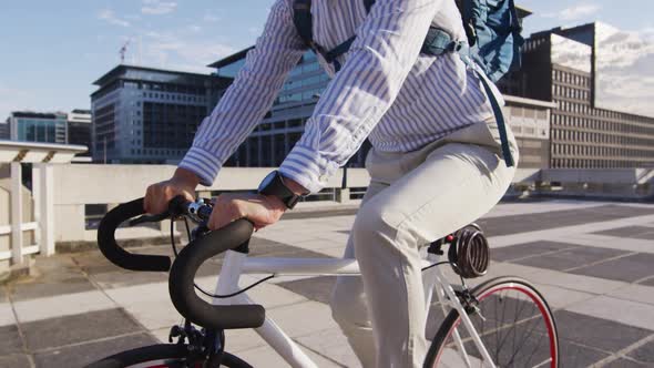Asian man with backpack riding bicycle on the roof of corporate park alt