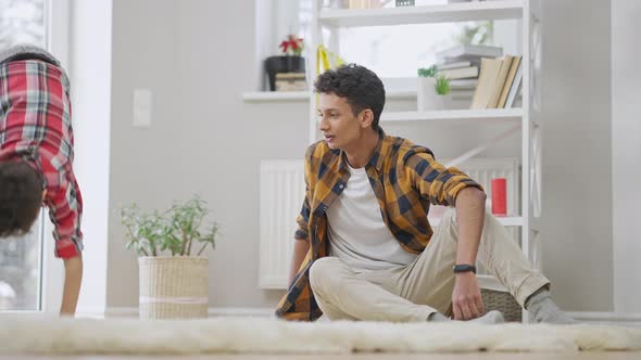 Excited Middle Eastern Teenager Admiring Little Boy Doing Somersault and Giving Highfive to Brother alt