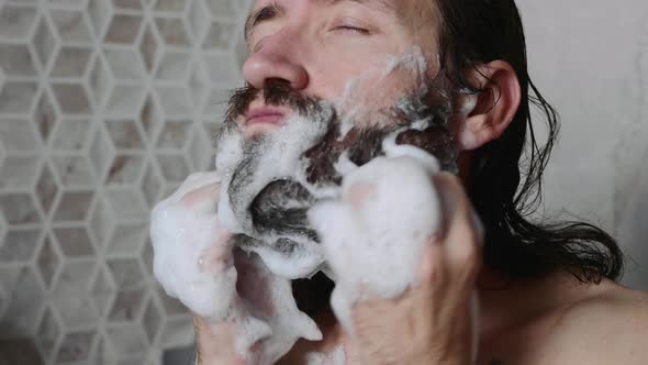 Man is Washing His Beard with Shampoo and Foam in the Shower
