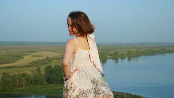 Seductive Woman in Loose Dress and Scarf Poses on River Bank alt