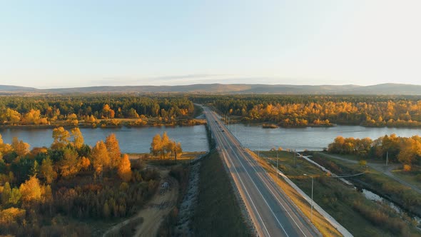 Aerial View of Cars Riding Across Bridge in the Autumn Forest