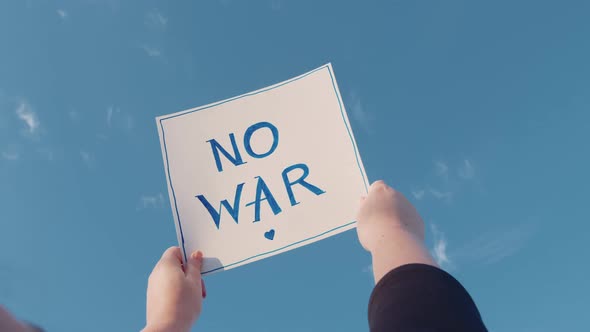 Closeup of a Cardboard Sign with the Inscription No War on the Blue Sky