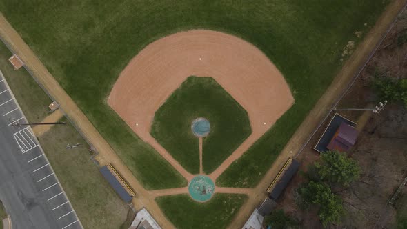 Top down view of empty ball field in autumn. Bases still on the field. Green grass and dirt.