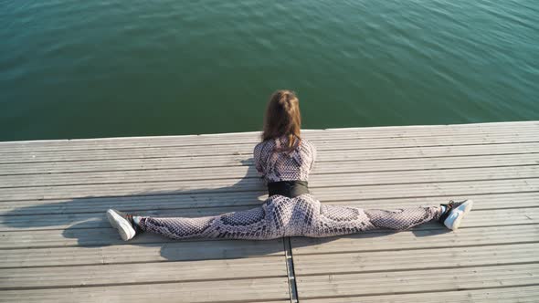 girl sitting in splits pier next beautiful lake Yoga and stretching in open air alt