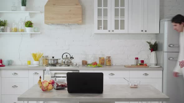 Hurrying Young Man Running in Kitchen Eating Morning Cereals with Milk Checking Time on Watch alt