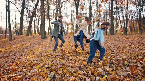 Young Parents and Little Daughter Laughing and Throwing Yellow Foliage at Each Other Playing in alt