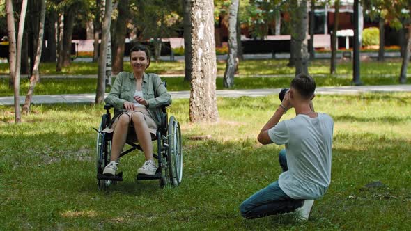 Woman in a Wheelchair and Her Friend Spending Time at the Summer Park and the Man Taking a Picture alt